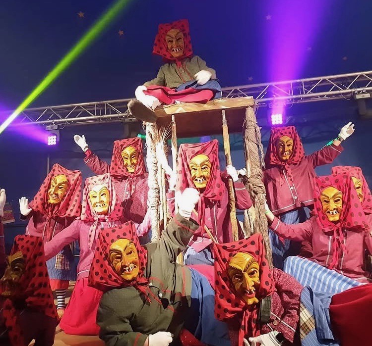 Auftritt der Hottscheck Hexen in Formation mit traditionellen Masken und Kostümen auf der Bühne