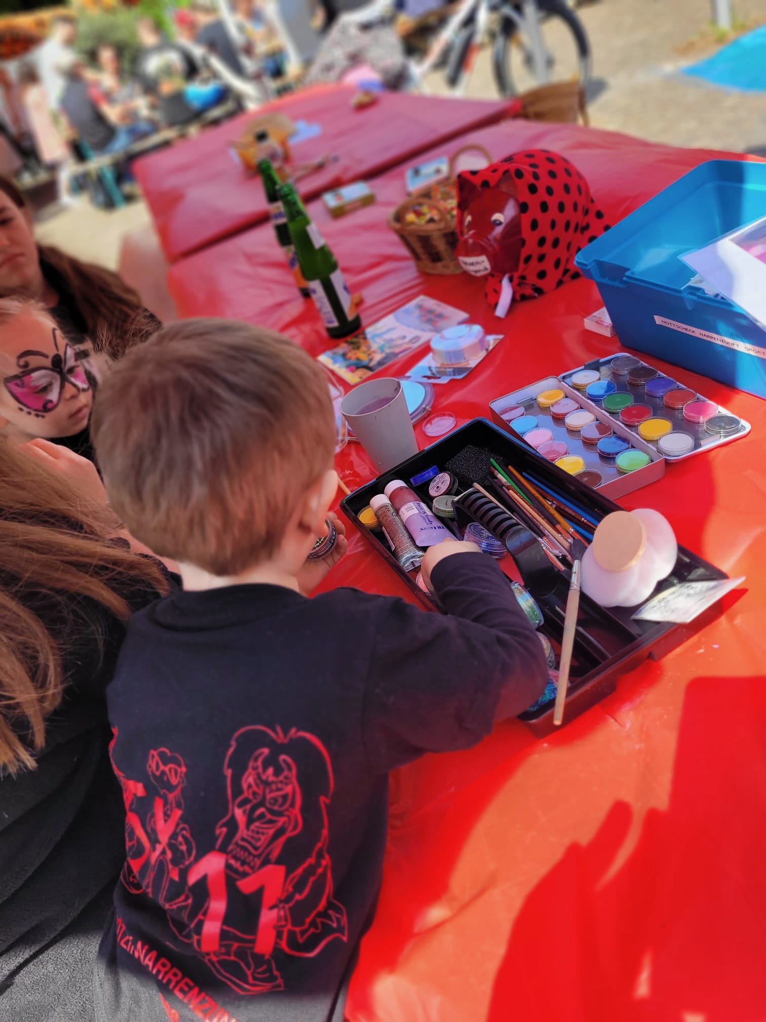Kind wird am Schminktisch beim Weinmarkt Grötzingen bunt geschminkt