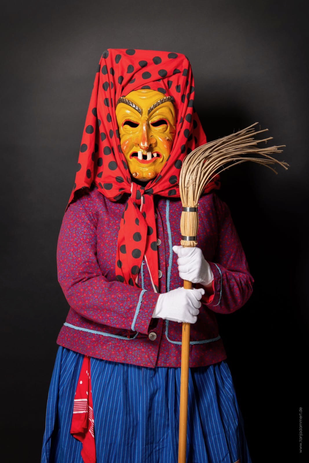 Hottscheck-Hexe im traditionellen roten Häs mit Holzmaske und Besen
